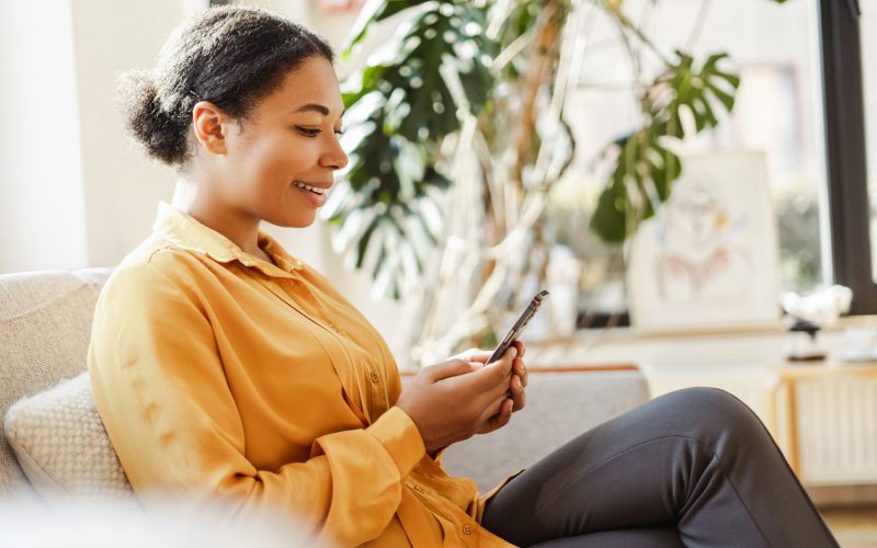 Modern smiling African American business woman, freelancer holding mobile phone